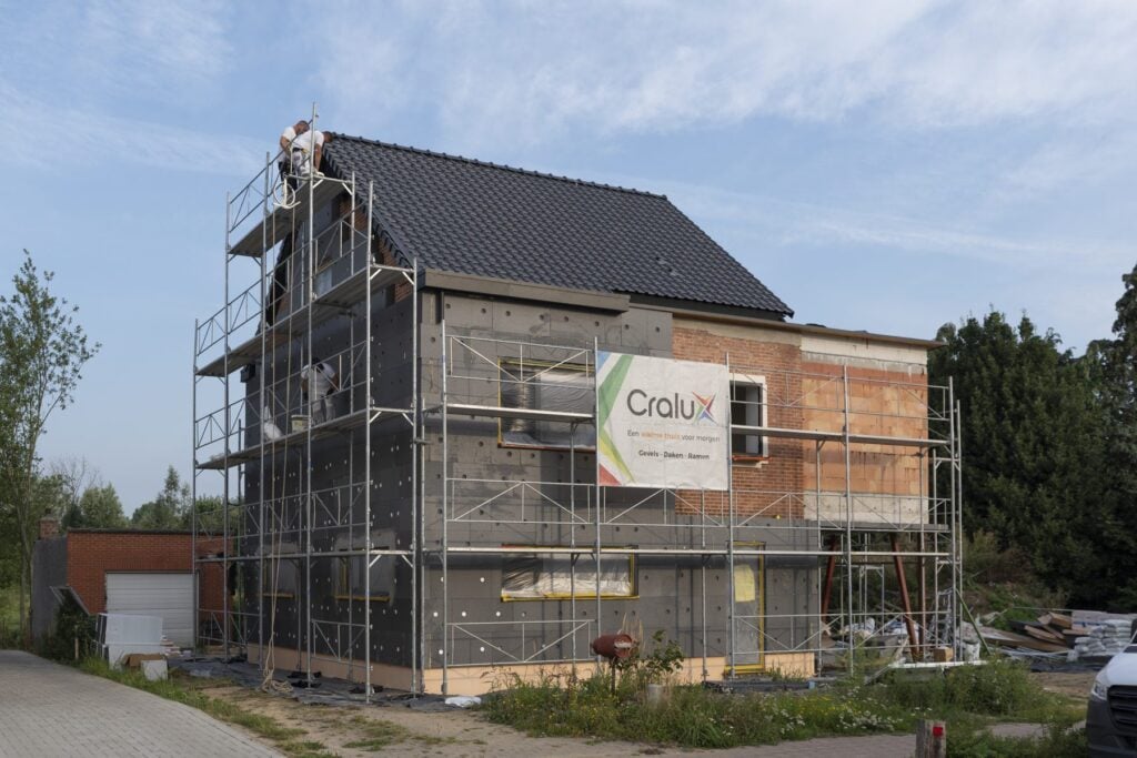 Cralux totaalrenovatie Zemst: nieuw dak, gevelisolatie en crepi in uitvoering, met steigers en Cralux-werfbanner